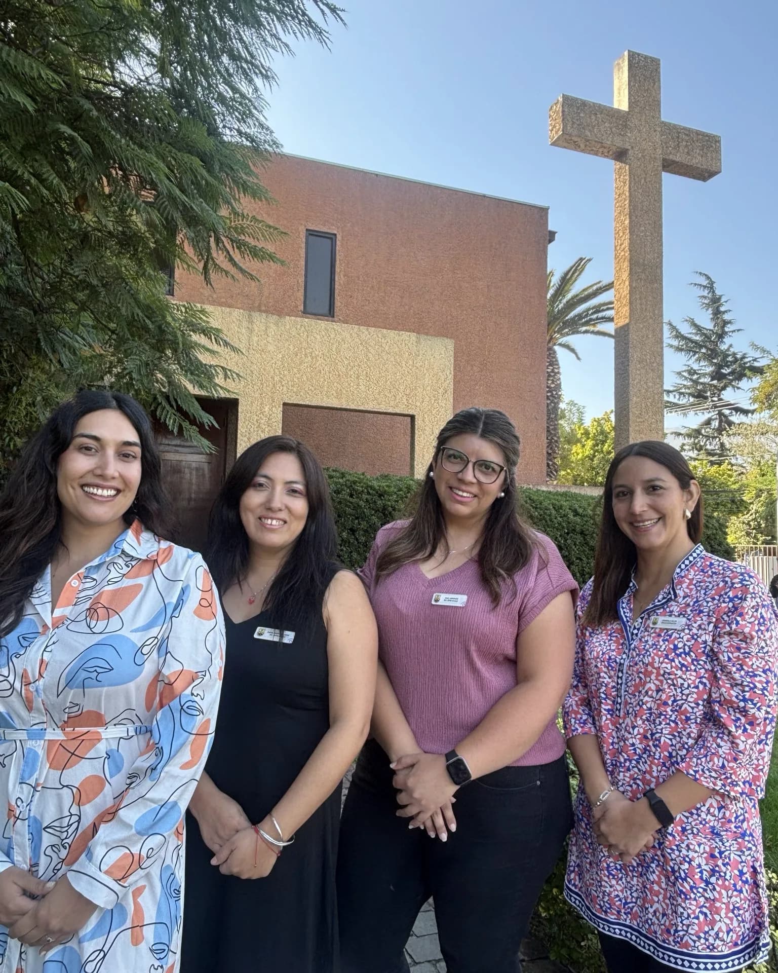 Las cuatro profesionales del Equipo de Inclusión del colegio, sonriendo frente a la capilla y la cruz.