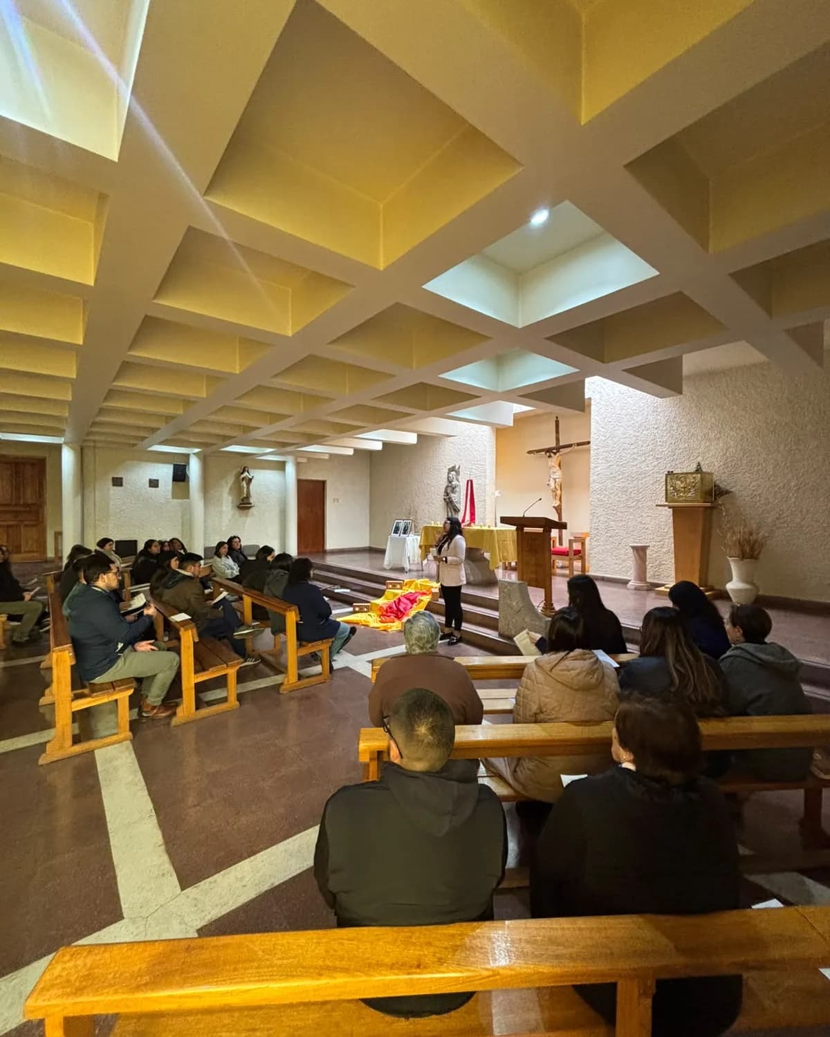 La comunidad reunida en las bancas de la capilla del colegio durante un encuentro, con el crucifijo y el altar al fondo.