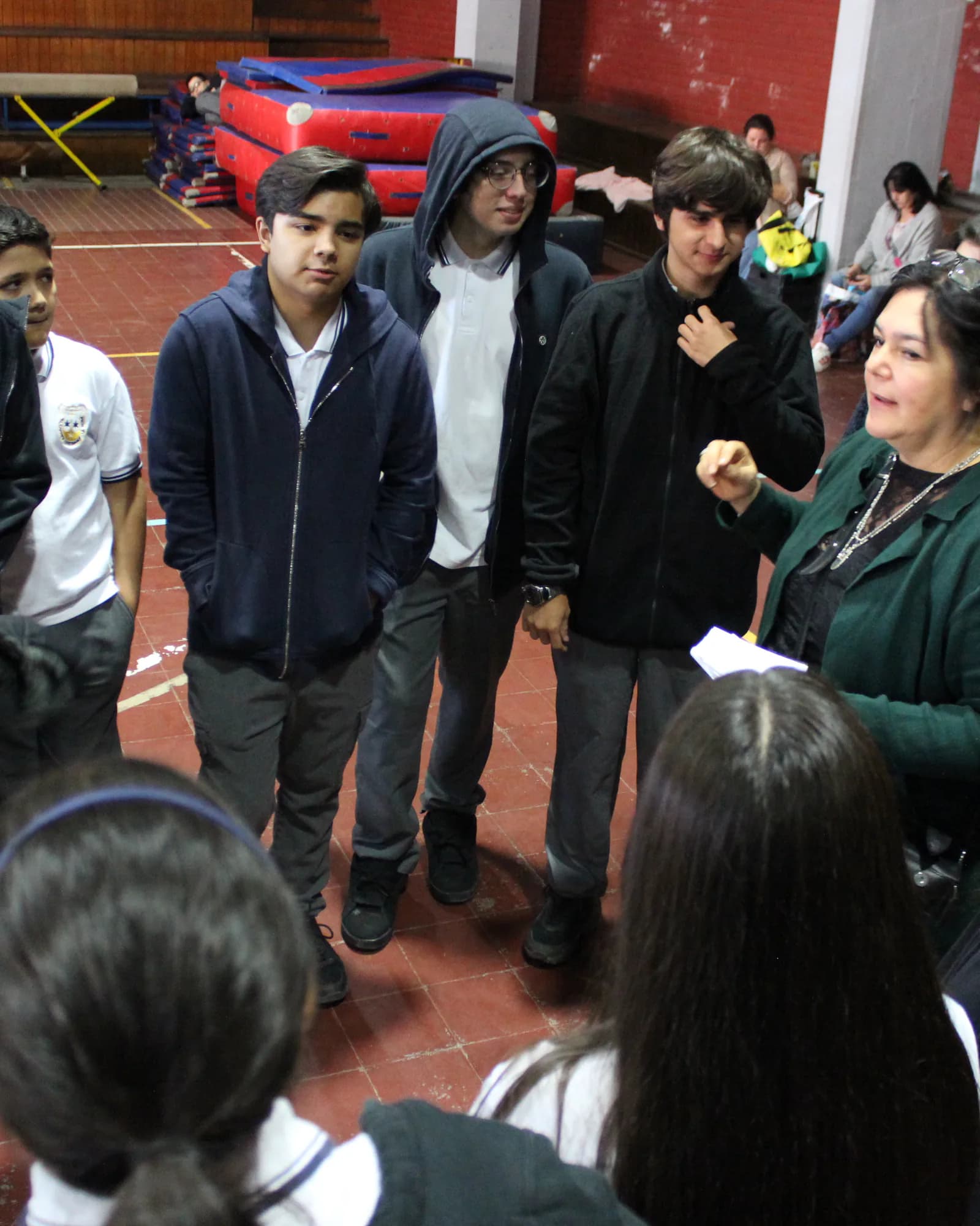 Una adulta conversa con un grupo pequeño de estudiantes durante una actividad escolar.