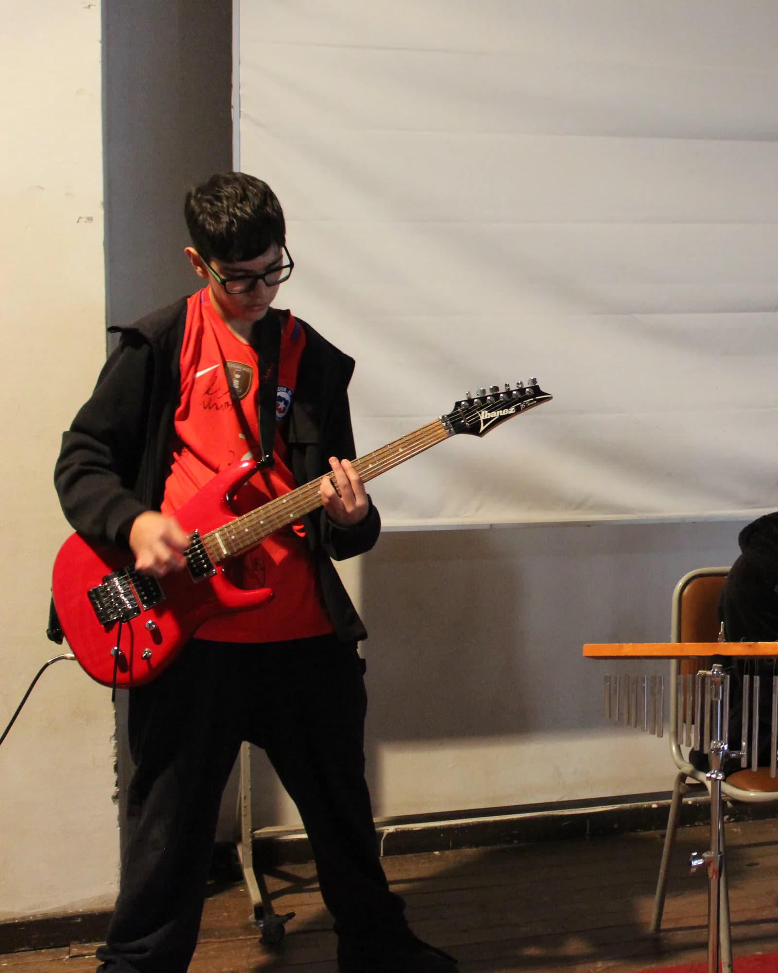 Estudiante toca la guitarra durante una presentación musical del colegio.