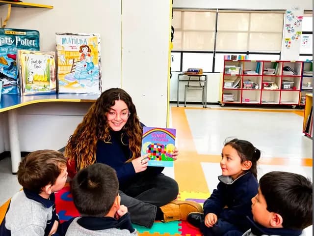 Una educadora lee un cuento a un grupo de niños en la biblioteca del colegio.