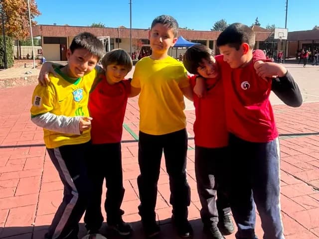 Estudiantes posan abrazados con una pelota en el patio del colegio.