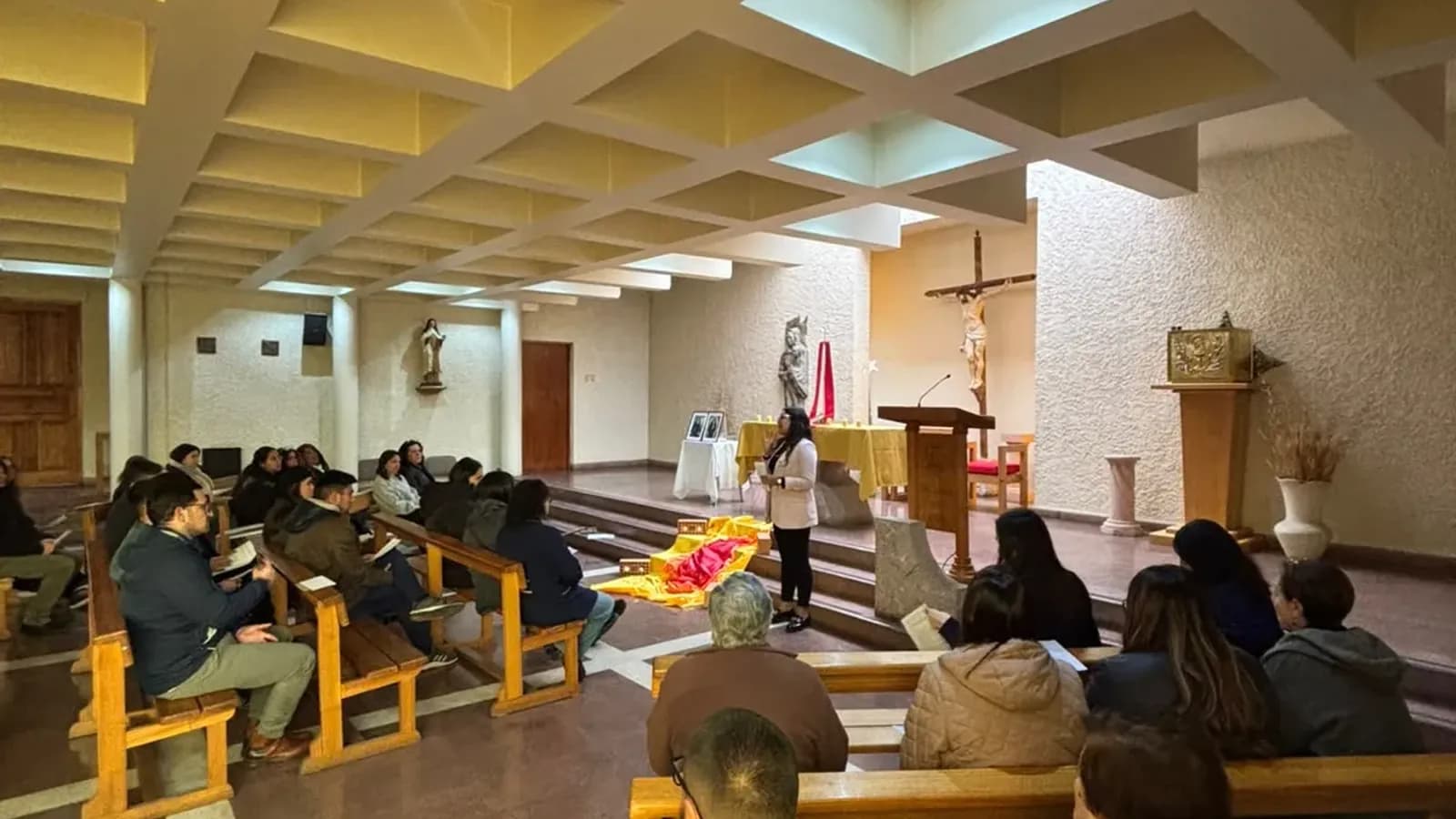La comunidad reunida en las bancas de la capilla del colegio durante un encuentro, con el crucifijo y el altar al fondo.